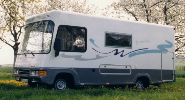 BAWEMO Dreamliner Wohnmobil auf einer Frühlingswiese vor blühenden Bäumen